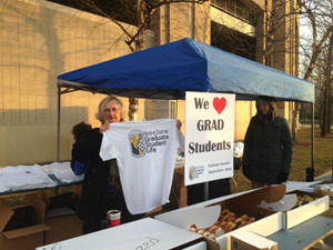 Graduate School and program administrators and staff handing out coffee, cocoa, pastries, and T-shirts to graduate students