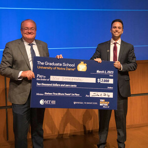 Interim Dean of the Graduate School and 3MT judge Tom Fuja presents the 2023 3MT first-prize check to Ph.D. candidate Alex Boomgarden.